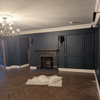 Navy paneled living room with herringbone flooring and wood-burning stove