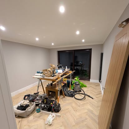 Room with light grey walls and herringbone wood floor during renovation